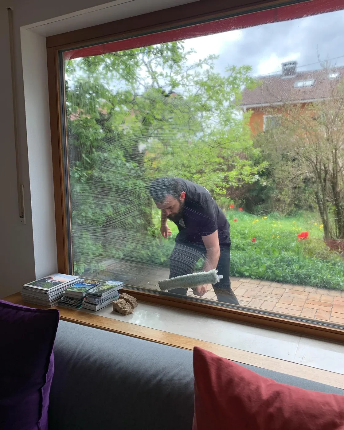 Mitarbeiter von Modus seift ein großes Wohnzimmerfenster von außen ein