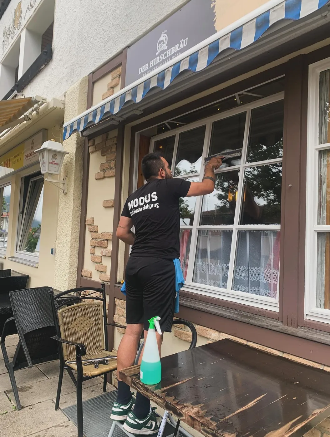 Mitarbeiter von Modus reinigt die Fenster einer Gaststätte von außen