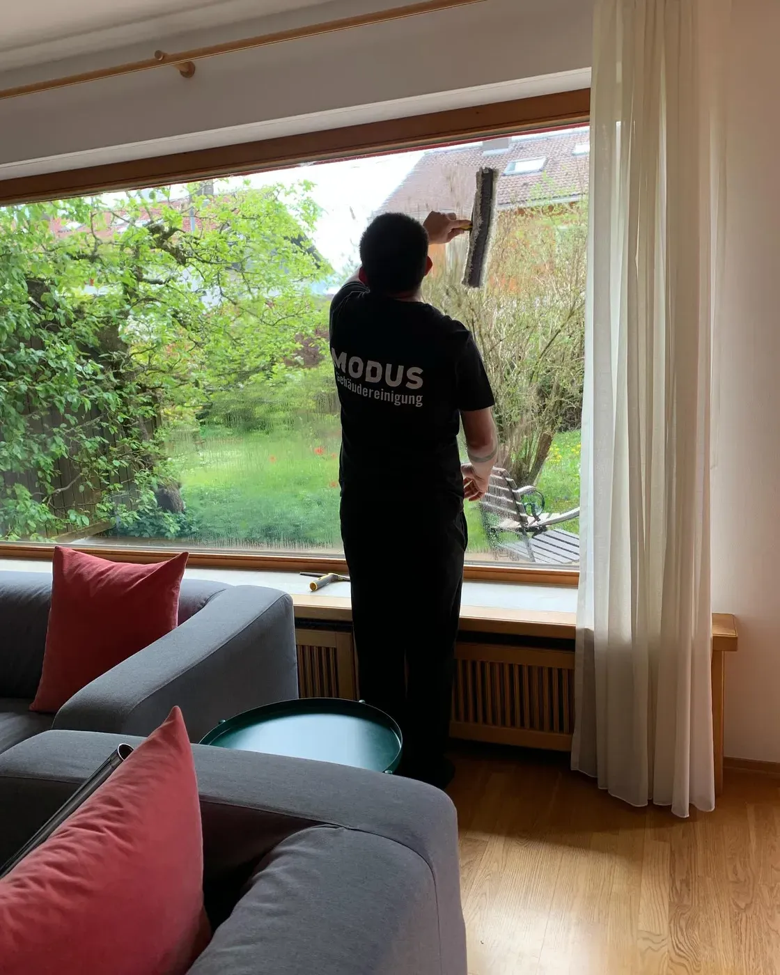 Mitarbeiter von Modus Gebäudereinigung bei der Fensterreinigung an einer großen Glasfront