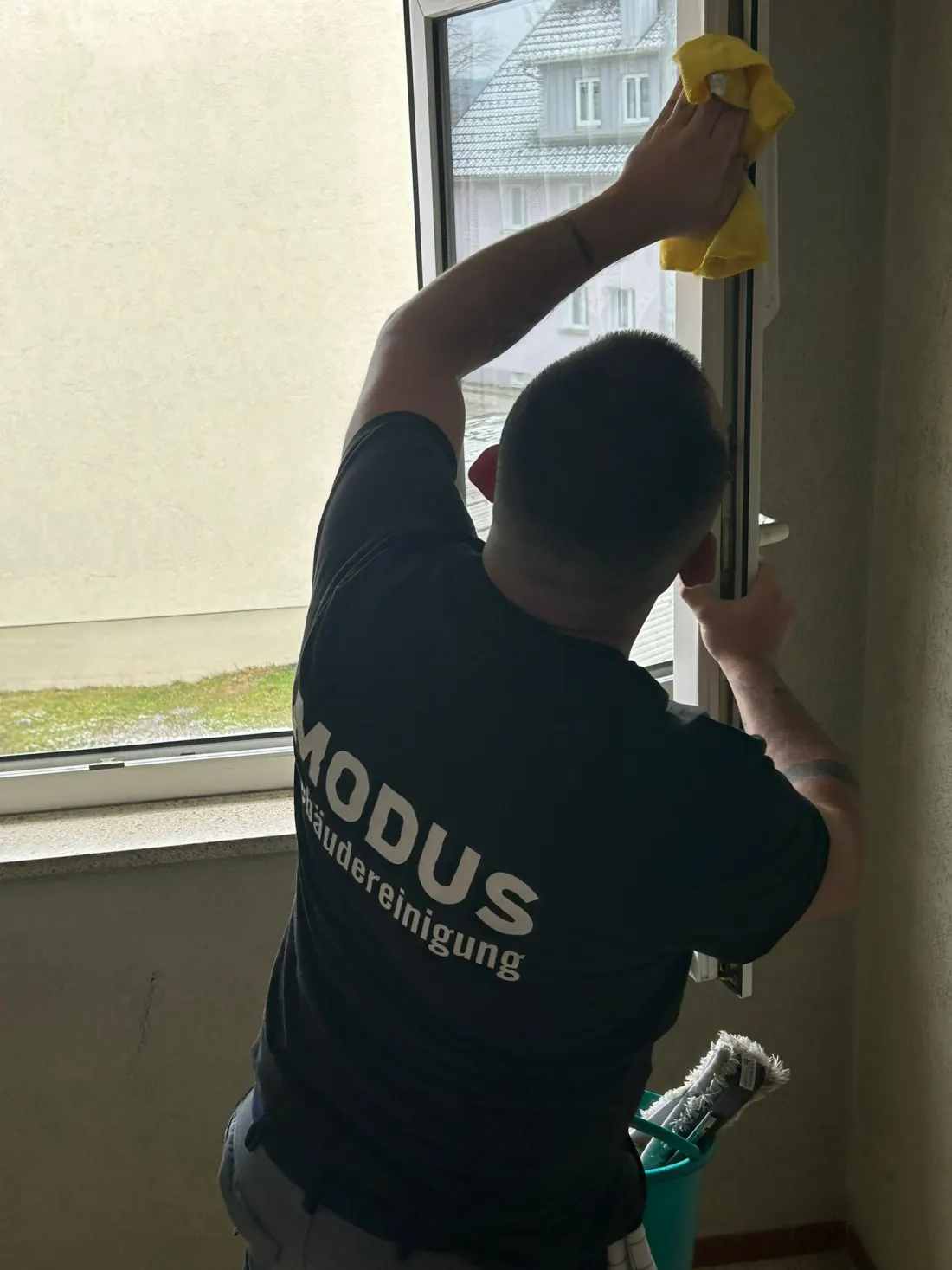 Mitarbeiter von Modus reinigt ein Treppenhausfenster