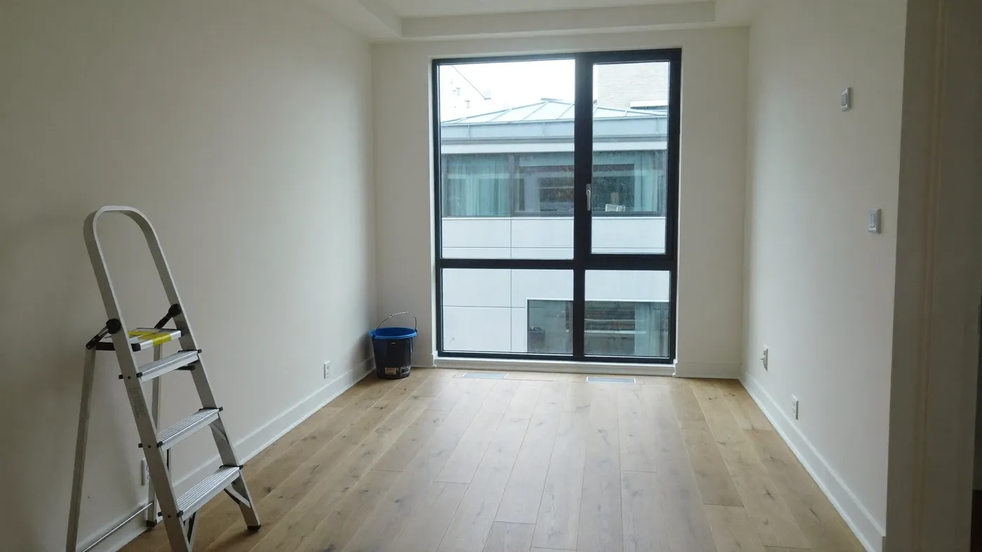 Leerer Neubauraum mit Fenster und Leiter nach der Bauendreinigung (Symbolbild)